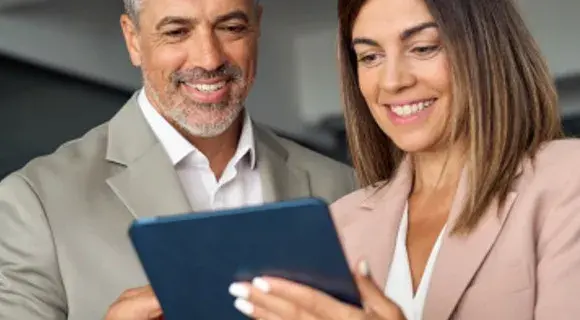 Man and woman looking at a tablet smiling